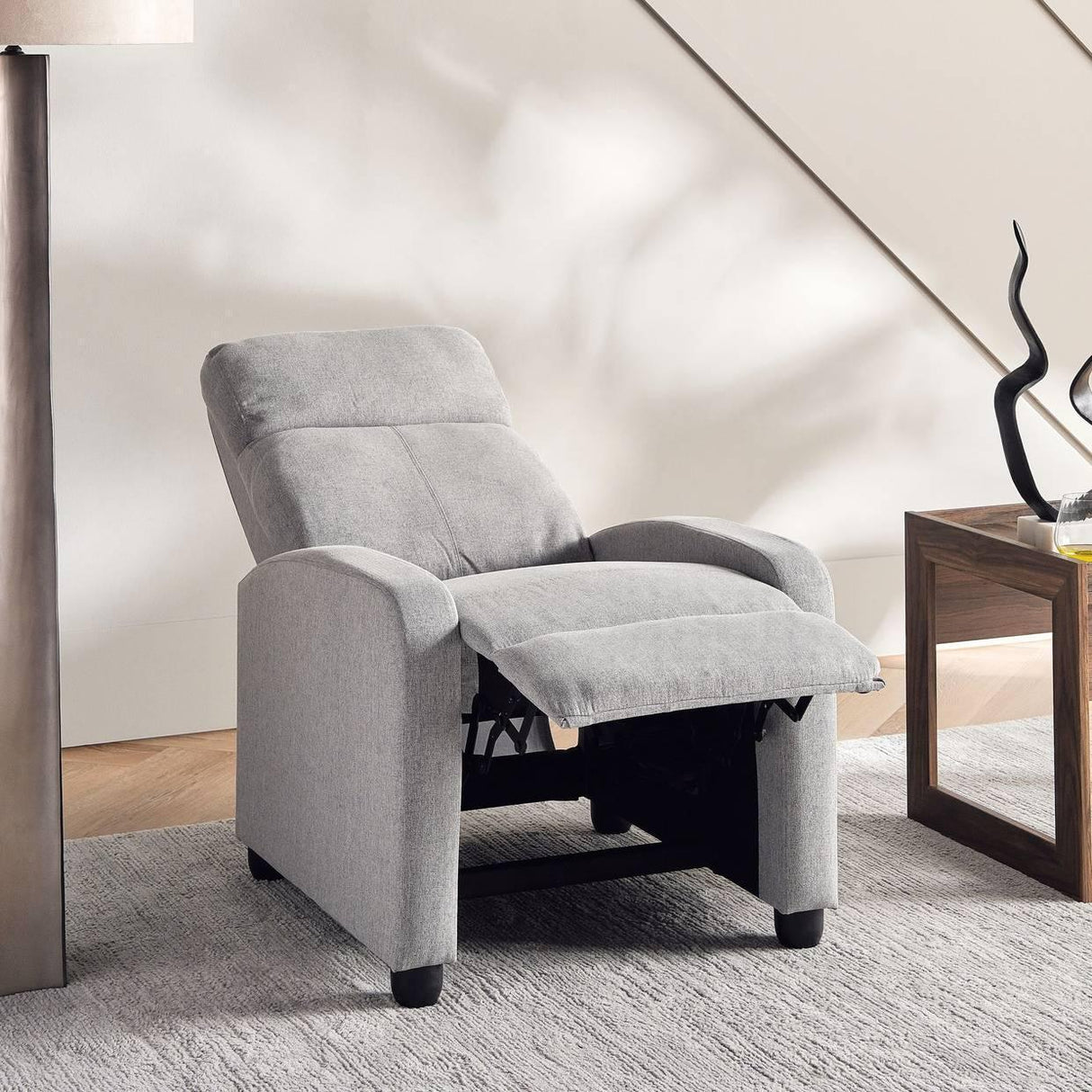Modern light gray recliner chair in a living room with a wooden side table