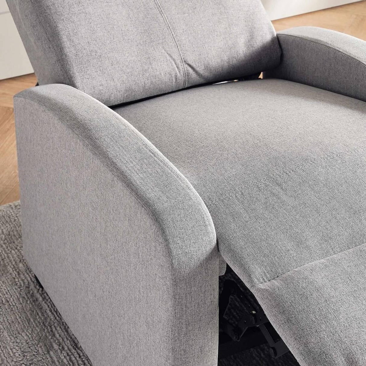 Modern light gray fabric recliner chair with extended footrest on a textured rug