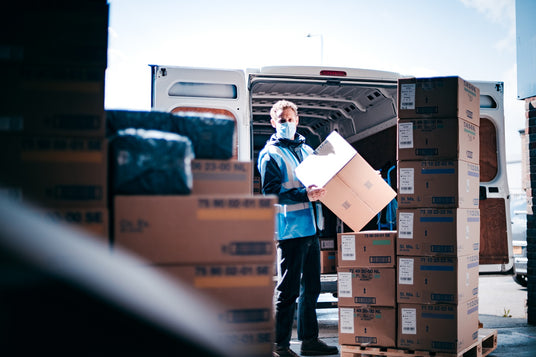 HOCC delivery worker in mask unloading boxes from van, online shopping UAE
