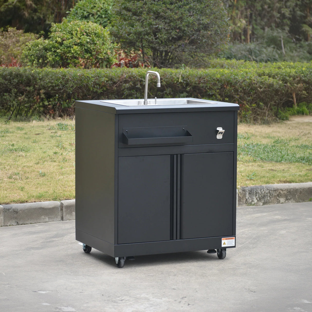 Black outdoor mobile sink cabinet with faucet and storage on wheels in garden setting
