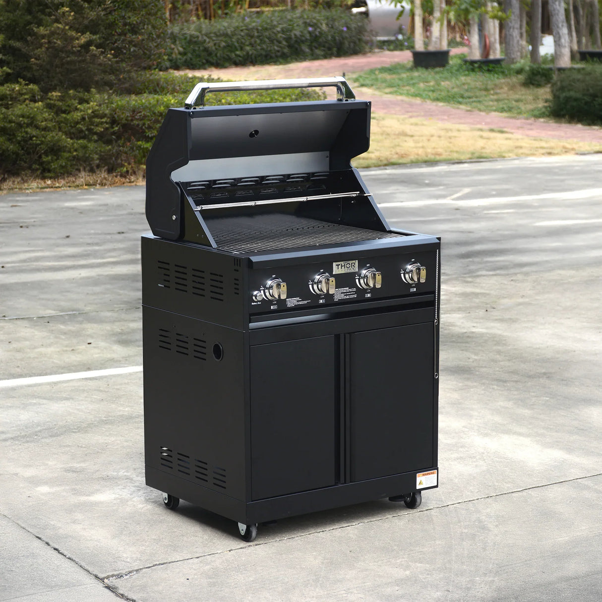 Black outdoor gas grill with four burners and open lid on a patio area