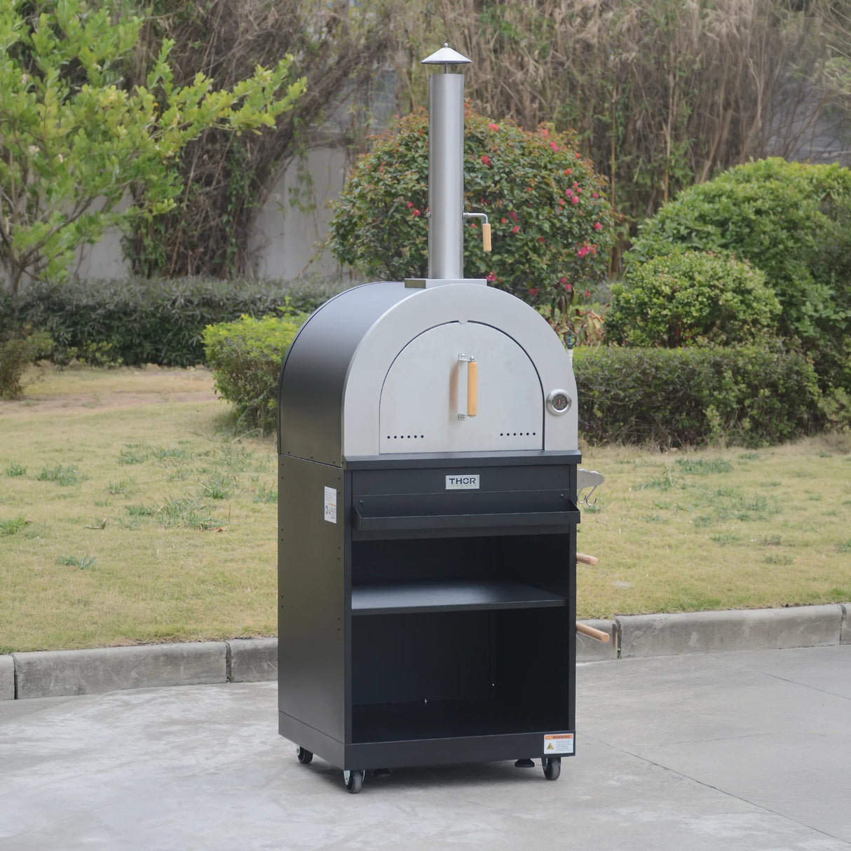 Outdoor wood-fired pizza oven with chimney, stainless steel door, and storage shelves on wheels