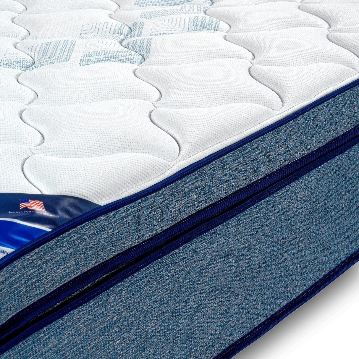 Close-up of hybrid mattress with white quilted top and blue fabric sides, American flag label