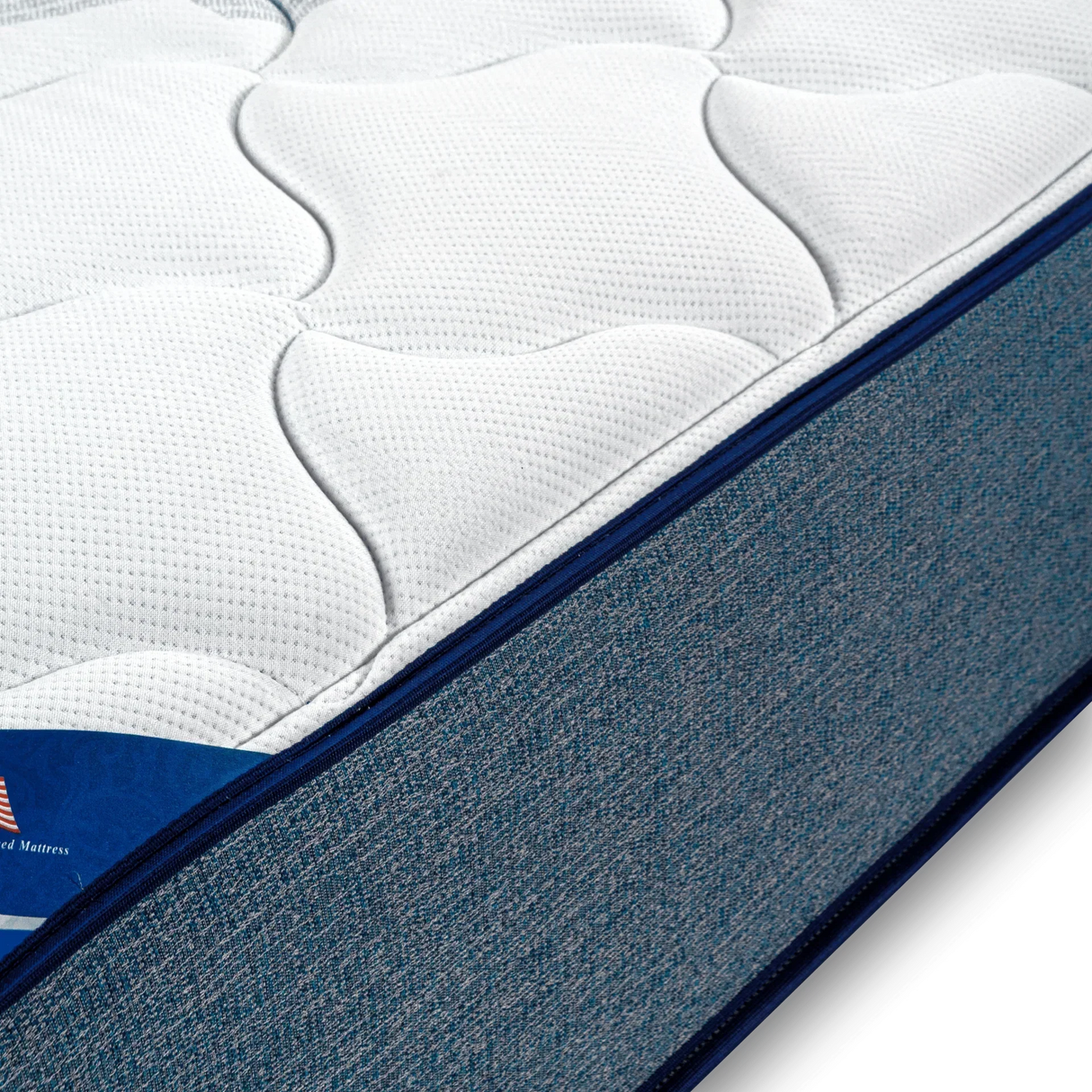 Close-up of hybrid mattress with textured white top and blue fabric sides
