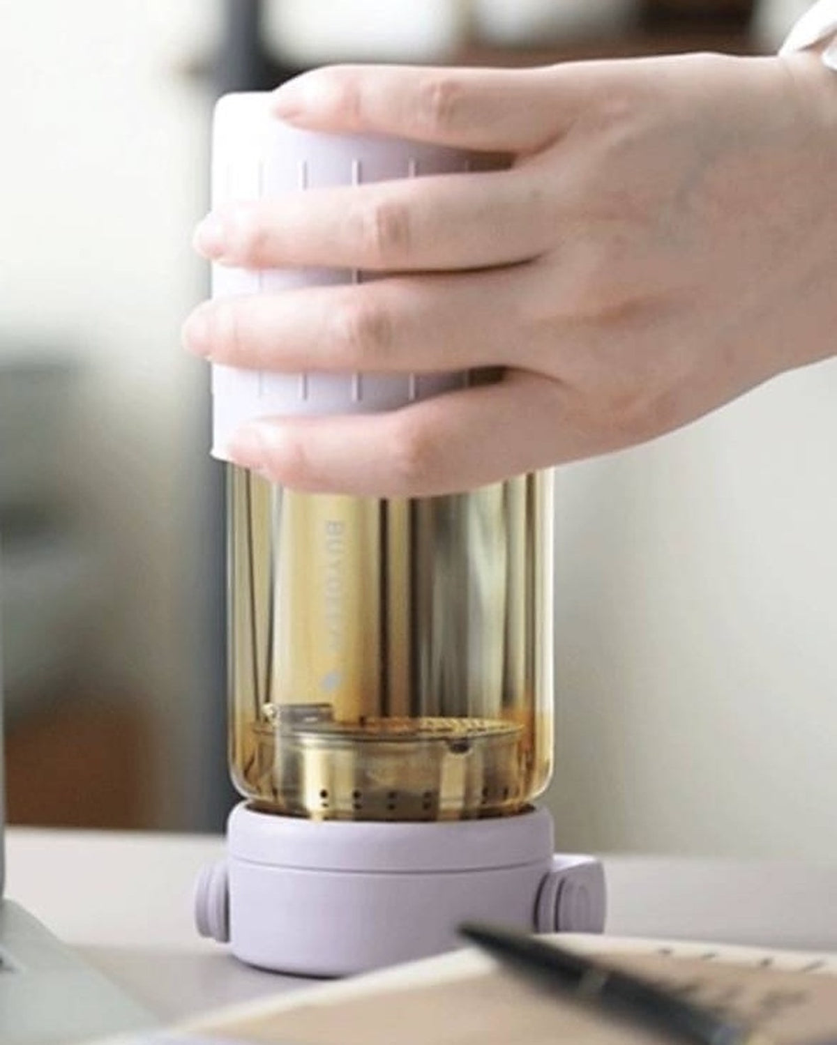 BUYDEEM DG45 Glass Tea Tumbler with Titanium Infuser 470ml – lilac tumbler held upside down for brewing on a desk