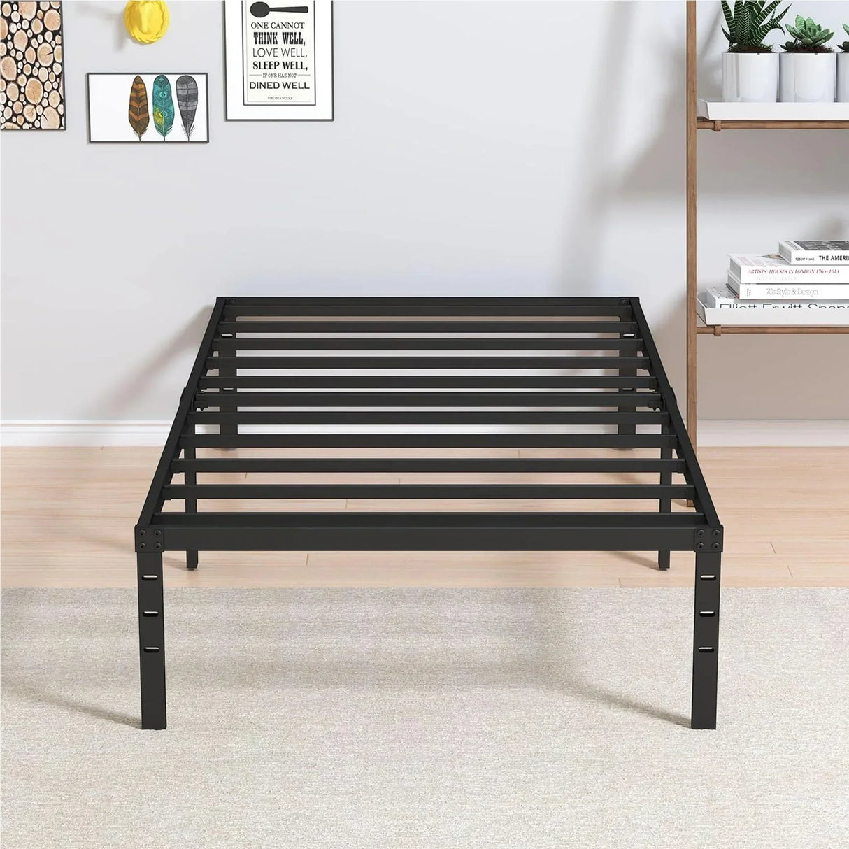 Black metal bed frame on light wood floor with wall art, shelf, and potted plants, HOCC UAE