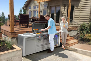 Man grilling at modern outdoor kitchen with stainless steel grill and refrigerator on patio