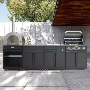 Modern outdoor kitchen setup with black cabinets, pizza oven, sink, and gas grill on patio