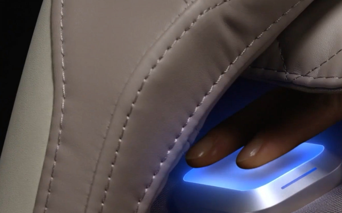 Fingers resting on the glowing health sensor in the right armrest