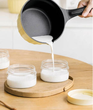 BUYDEEM CP143 Non-Stick Milk Pan 20cm with Glass Lid – yellow pan pouring milk into glass jars