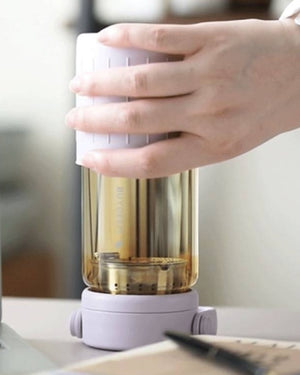 BUYDEEM DG45 Glass Tea Tumbler with Titanium Infuser 470ml – lilac tumbler held upside down for brewing on a desk
