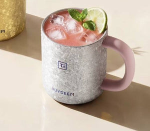 BUYDEEM T502 Pure Titanium Insulated Mug with Lid 430ml – silver pig mug with an iced pink drink, lime and mint on a cream table